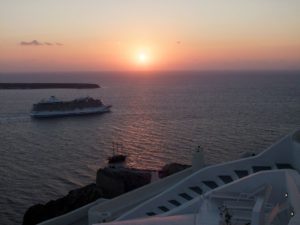 Santorin-Landausflüge: Ein Kreuzfahrtschiff verlässt Santorin bei Sonnenuntergang.