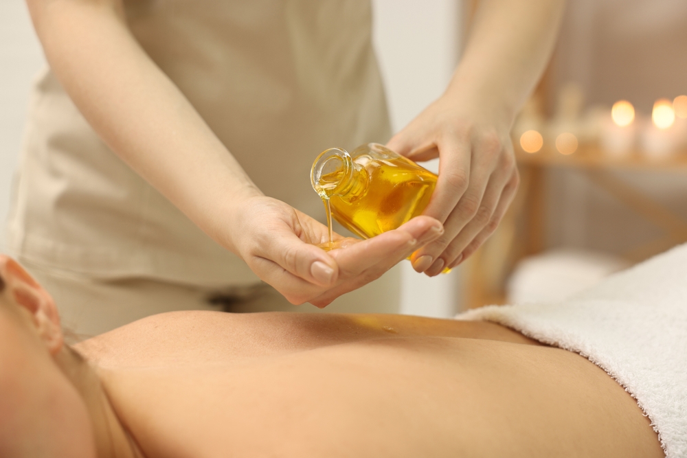 Massageöl wird auf dem Rücken einer Person verteilt