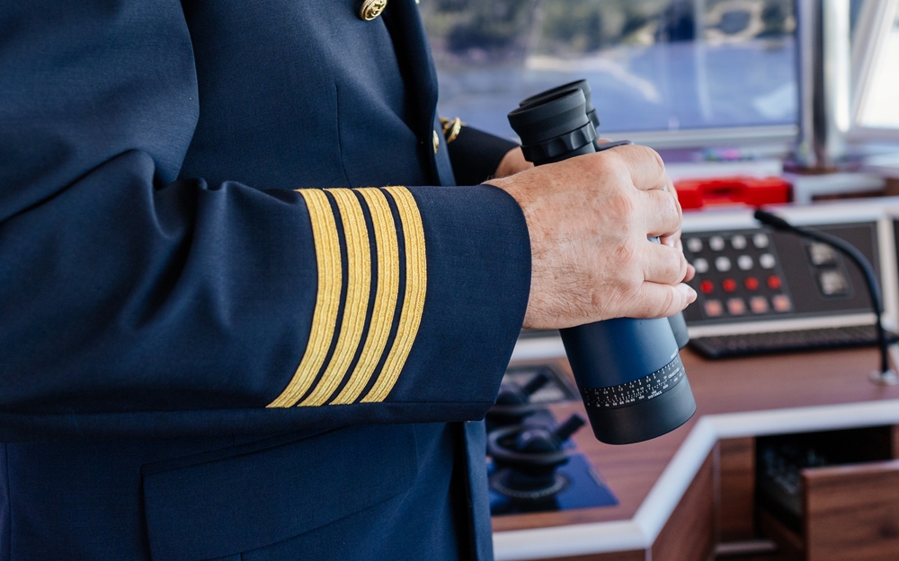 Die Hände eines Kapitäns, die ein Fernglas halten