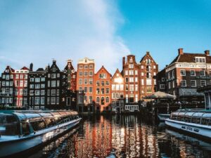 Eine Reihe Giebelhäuser spiegelt sich im Wasser einer Amsterdamer Gracht