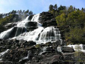 Landausflugsgäste bestaunen den Wasserfall Tvindefossen bei einem Ausflug