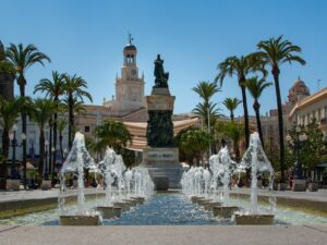 Der Plaza de San Juan de Dios: Im Vordergrund das Wasserspiel und Palmen und im Hintergrund das Rathaus