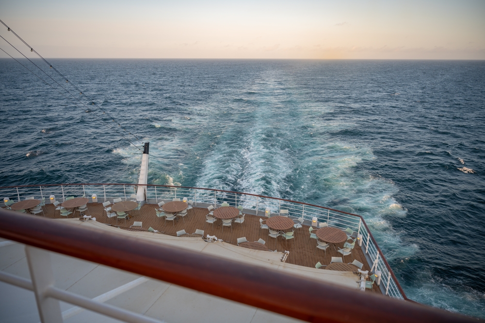 Das Deck eines Kreuzfahrtschiffes mit Tischen und Stühlen sowie Blick auf das Meer
