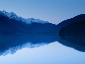 Blick auf Wasser mit eingeschneiter Bergkette im Hintergrund