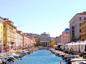 Blick auf den von Booten gesäumten Canal Grande in Triest mit der Kirche Sant'Antonio Taumaturgo im Hintergrund