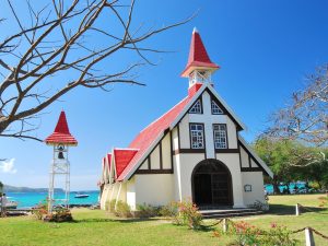 Das rote Dach der Kirche in Cap Malheureux hebt sich vom türkisfarbenen Wasser ab